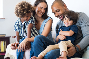 A happy family sitting on the couch laughing.